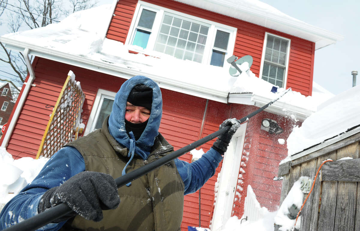 Walter Brennan clears snow from his roof using a roof rake after a blizzard pounded the region in West Haven, Conn. on Saturday February 9, 2013.
