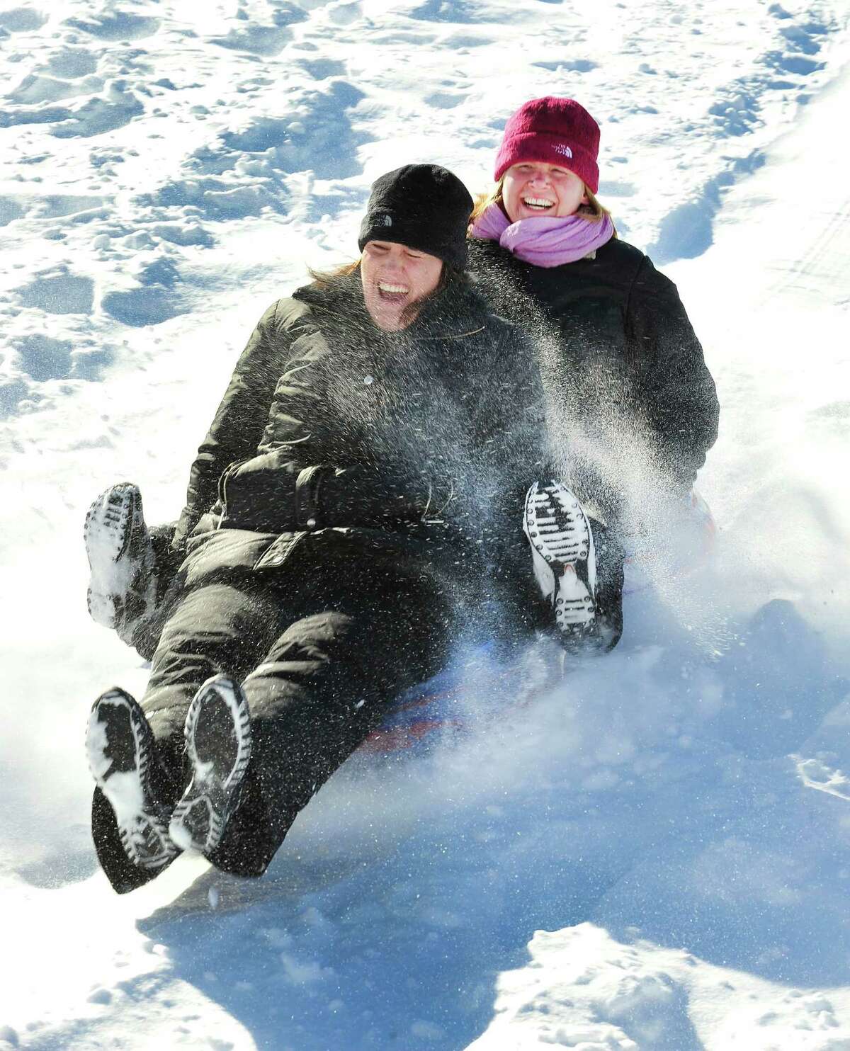 Kim Butera, left, and Erin Williams have fun sledding in the snow behind St. Gregory the Great Church in Danbury Saturday, Feb. 9, 2013.