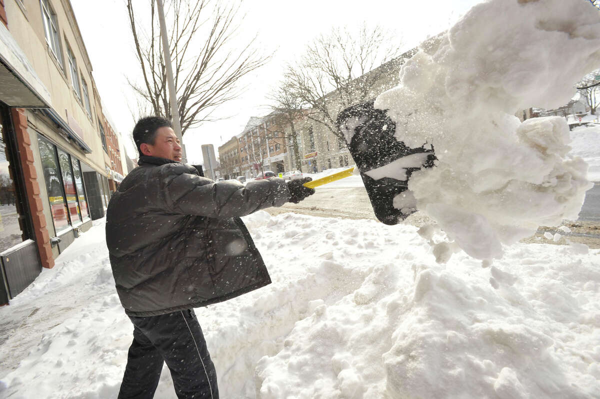 Shan Nee shovels out in front of his business on Main Street in Danbury on Saturday, Feb. 9, 2013.