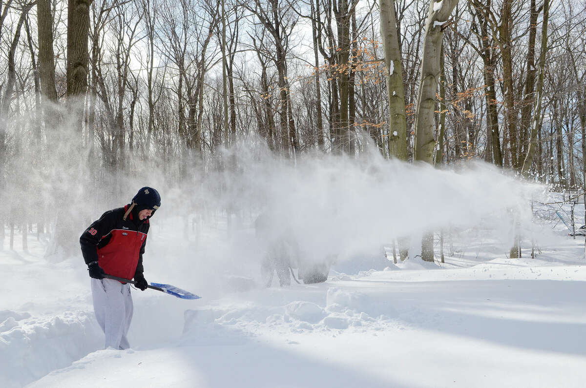 Dan Silvestri, 17, helps clear a path to his family's backyard wood pile in Southport, CT on Sat., Feb. 9, 2013, following a blizzard that dumped up to three feet of snow across the state. Silvestri's dad, Peter Silvestri, operates a snowblower in the background.