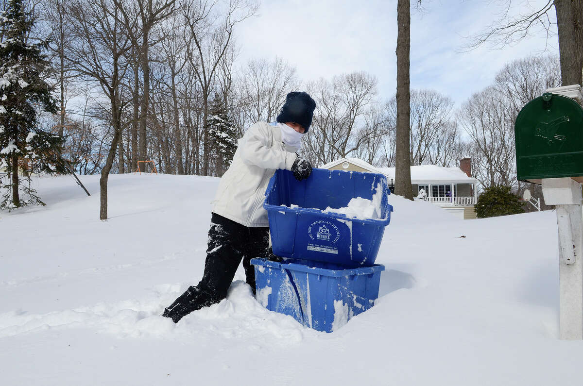 Sydney McArthur, 16, Fairfield, helps bring in the recycling bins at a friend's house in Southport, CT on Sat., Feb. 9, 2013, following a blizzard that dumped up to three feet of snow across the state. She wanted to get them in before the plows came.