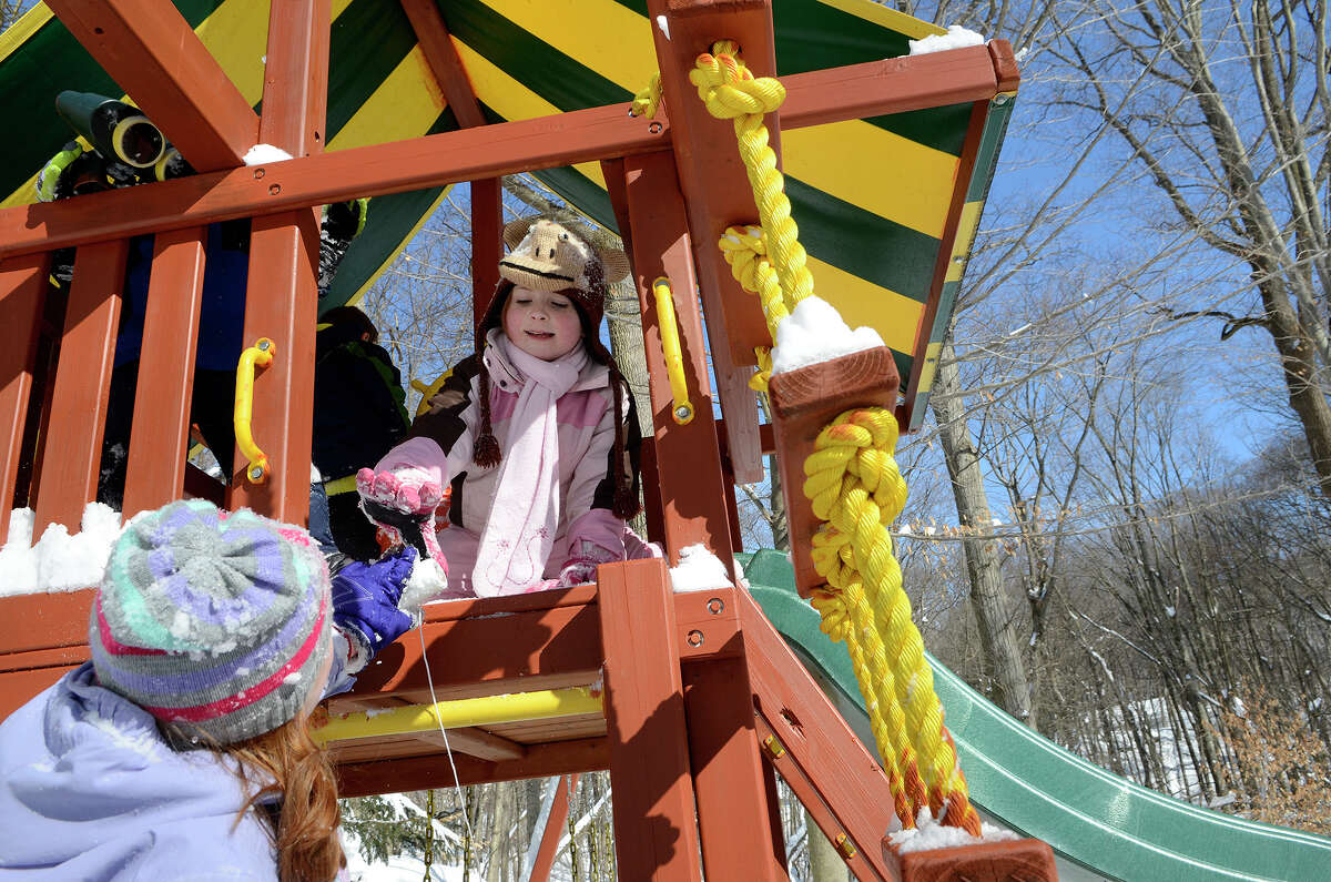 Molly Coccaro, 7, hands a roll of string to her sister Caroline Coccaro, 9, in their backyard playset as they make the best of a snowy day in Southport, CT on Sat., Feb. 9, 2013, following a blizzard that dumped up to three feet of snow across the state.