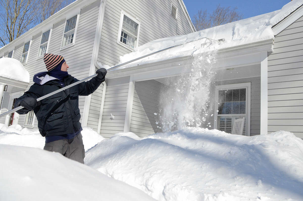 T.R. Coccaro uses a roof rake on his home as he contends with the snow in Southport, CT on Sat., Feb. 9, 2013, following a blizzard that dumped up to three feet of snow across the state.