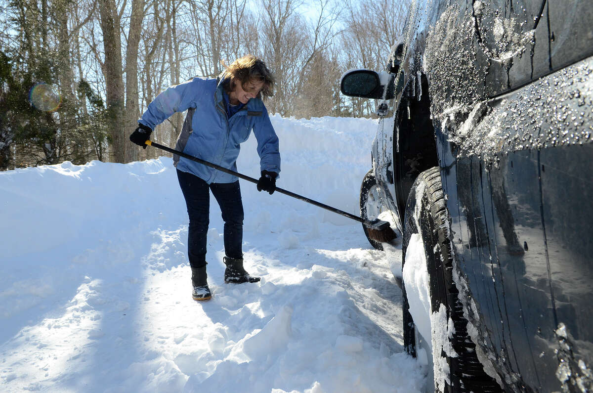 Julie Wyckoff clears snow from her car in Southport, CT on Sat., Feb. 9, 2013, following a blizzard that dumped up to three feet of snow across the state.