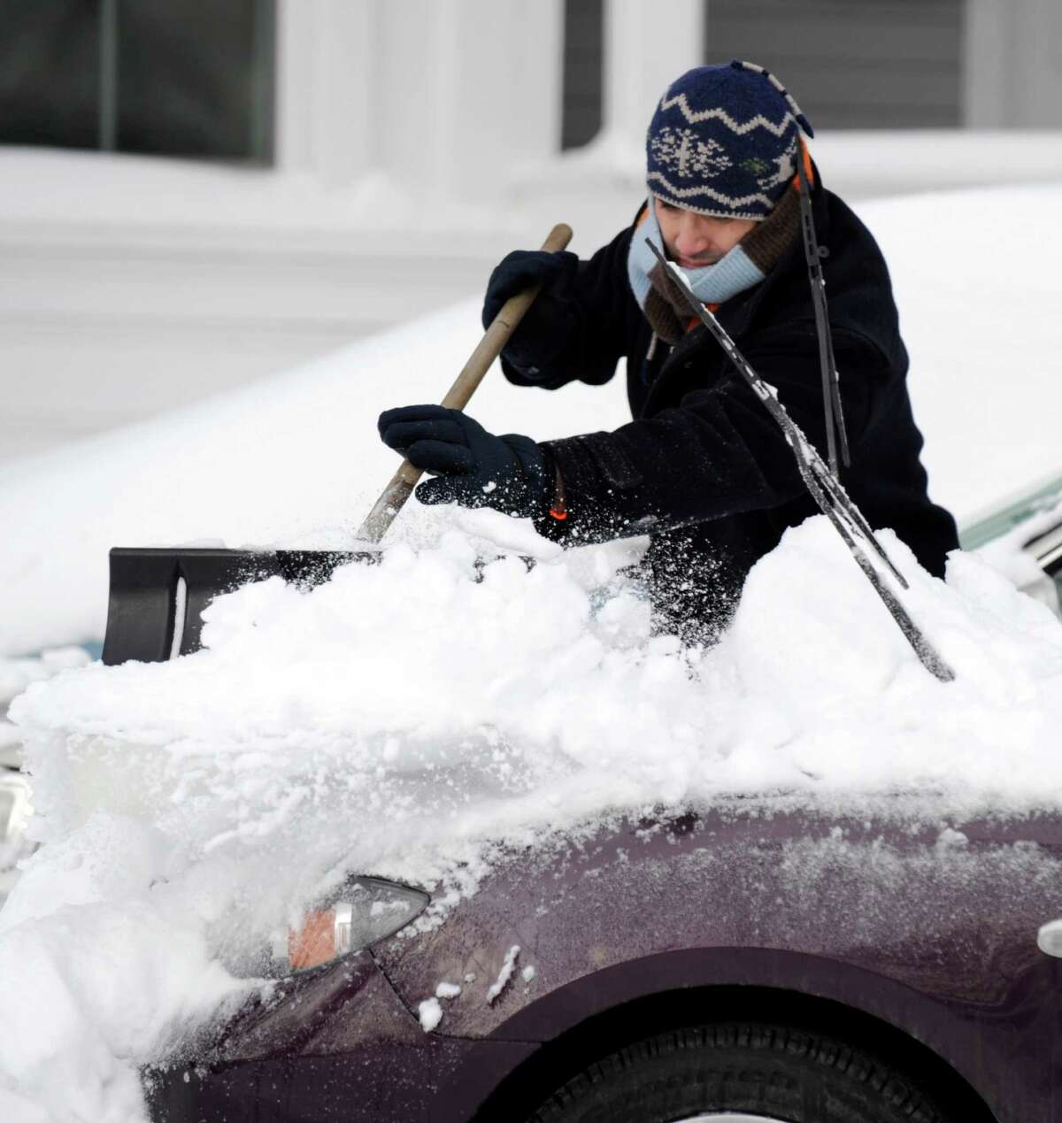 Italo Venegas cleans off his off his car on Grand Street in Bethel, Conn. Saturday, Feb. 9, 2013. A blizzard dumped almost two feet of snow on the Danbury area Friday and early Saturday morning.