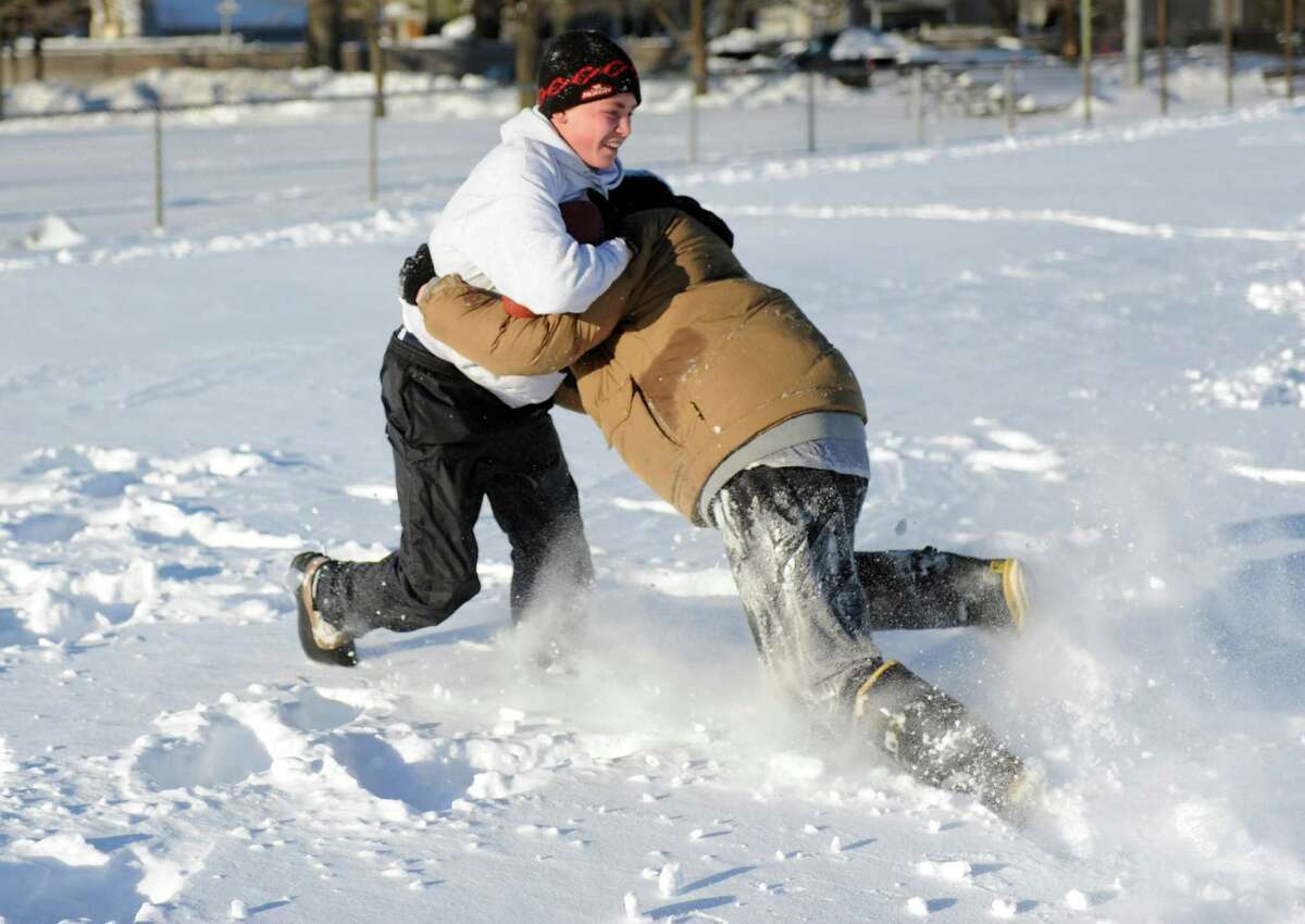 Timothy Mira, left, and Anthony Pampena Jr., right, play football in Cummings Park in Stamford, Conn., on Saturday, February 9, 2013.