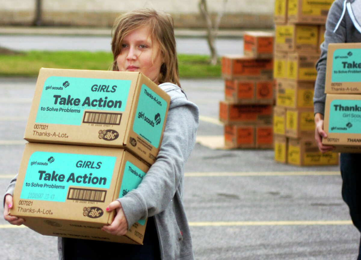 Junior Girl Scout Mackenzie Graham carries boxes of cookies to a waiting vehicle Saturday at Wesley United Methodist Church. A shipment of 60,000 boxes of cookies arrived there for the annual Girl Scout cookie sale.