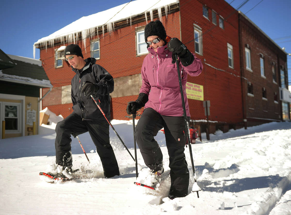 Their street still unplowed, Marc and Michelle Zahariades use snowshoes to travel down Factory Lane in Milford, Conn. on Sunday, February 10, 2013.