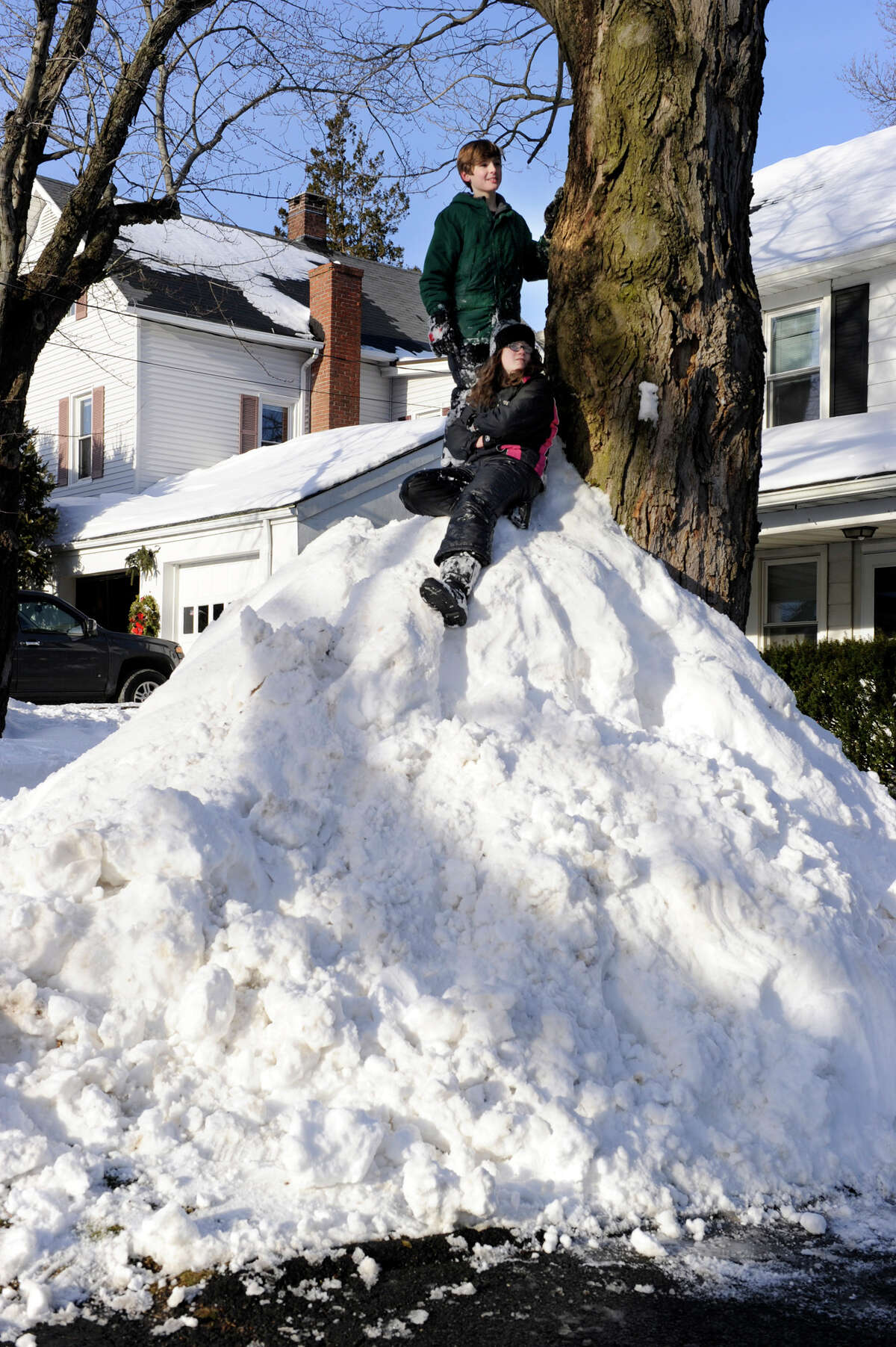 Haylee Hughes, 12, sitting, and Bryce Benson, 10, watch for cars to pass by the "mountain" of snow that Bryce and his father Chris, created against a tree at the family's home on Abbott Avenue in Danbury, Conn. Feb. 10, 2013. A blizzard dumped almost two feet of snow on the Danbury area all day friday and early Saturday morning.