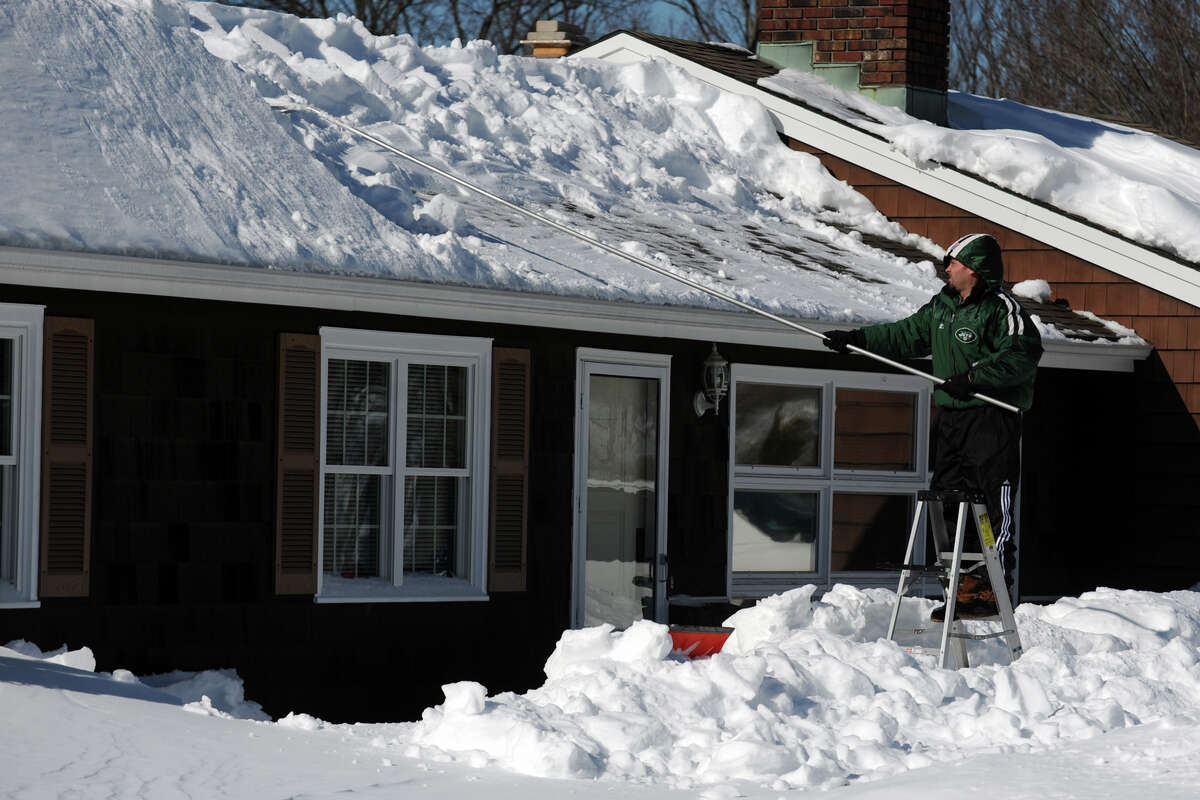Joe Monte uses a roof rake as he works to works to remove a large snow drift from the roof of his home on Eurika Ave., in Stratford, Conn., Feb. 10th, 2013.