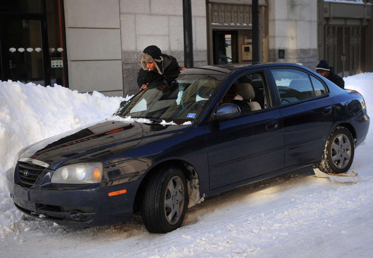 A man pushes out a stranded motorist on Main Street in downtown Bridgeport, Conn. on Sunday, February 10, 2013.