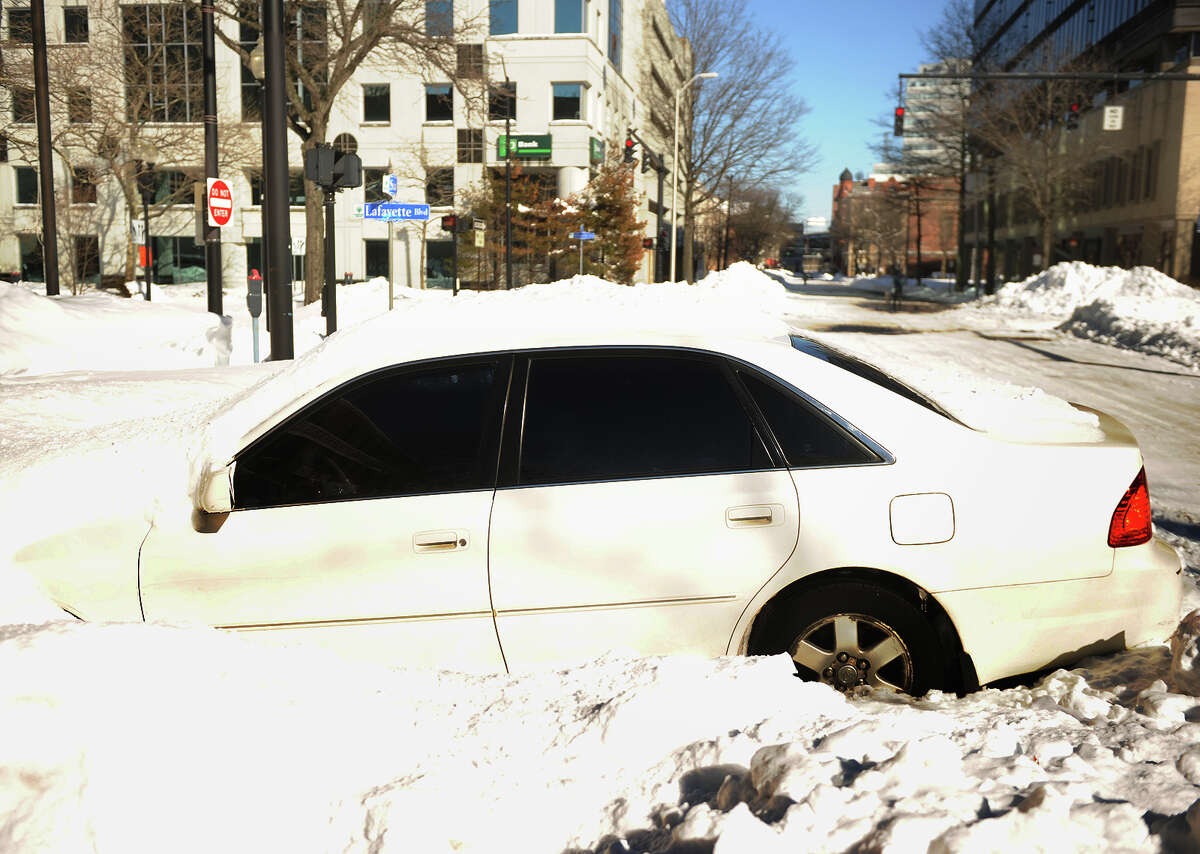 An abandoned car is buried in the snow on State Street in downtown Bridgeport, Conn. on Sunday, February 10, 2013.