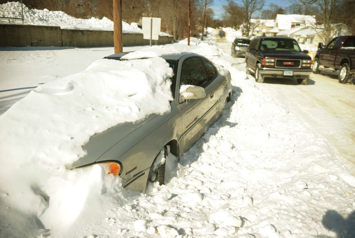 An abandoned car is buried in the snow on High Street in Milford, Conn. on Sunday, February 10, 2013.