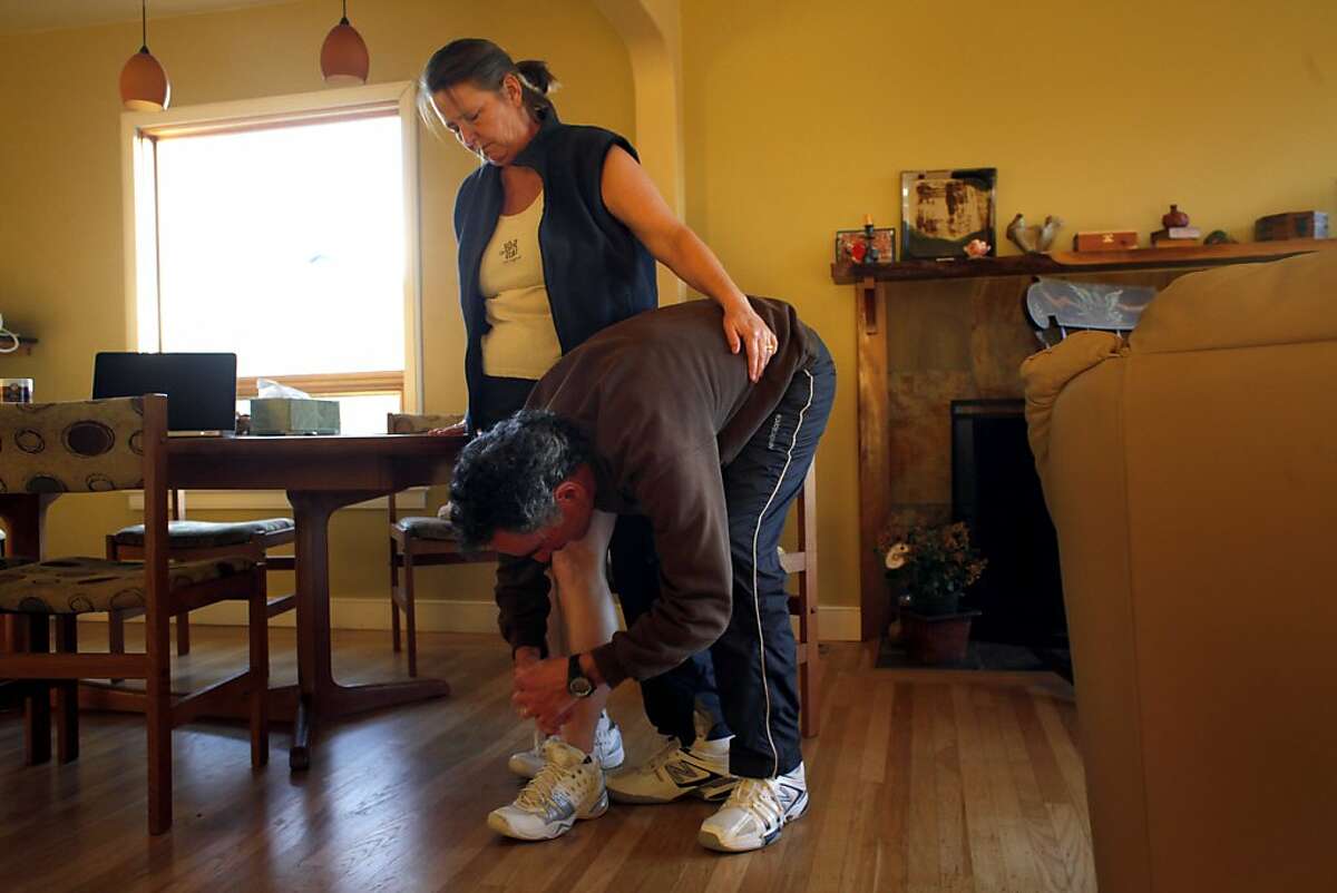 Sandy Rotenberg gets help from her husband Victor with tying her shoes at their home, Wednesday Feb. 6, 2013, in El Cerrito, Calif. Sandy received a metal- on metal hip implant in 2006 which was faulty and recalled. She has joined many other patients in suing the manufacturer, De Puy, for jumping through a loophole in FDA regulations allowing high risk surgical devices from going through clinical trials where they would be tested for safety and effectiveness.