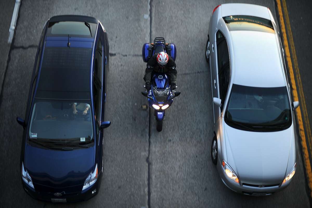 A motorcyclist lanesplits during evening commute on Highway 24 on Friday, Feb. 8, 2013, in Oakland, Calif.