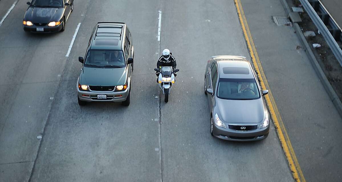 A motorcyclist lane splits during evening commute in Oakland, Calif.