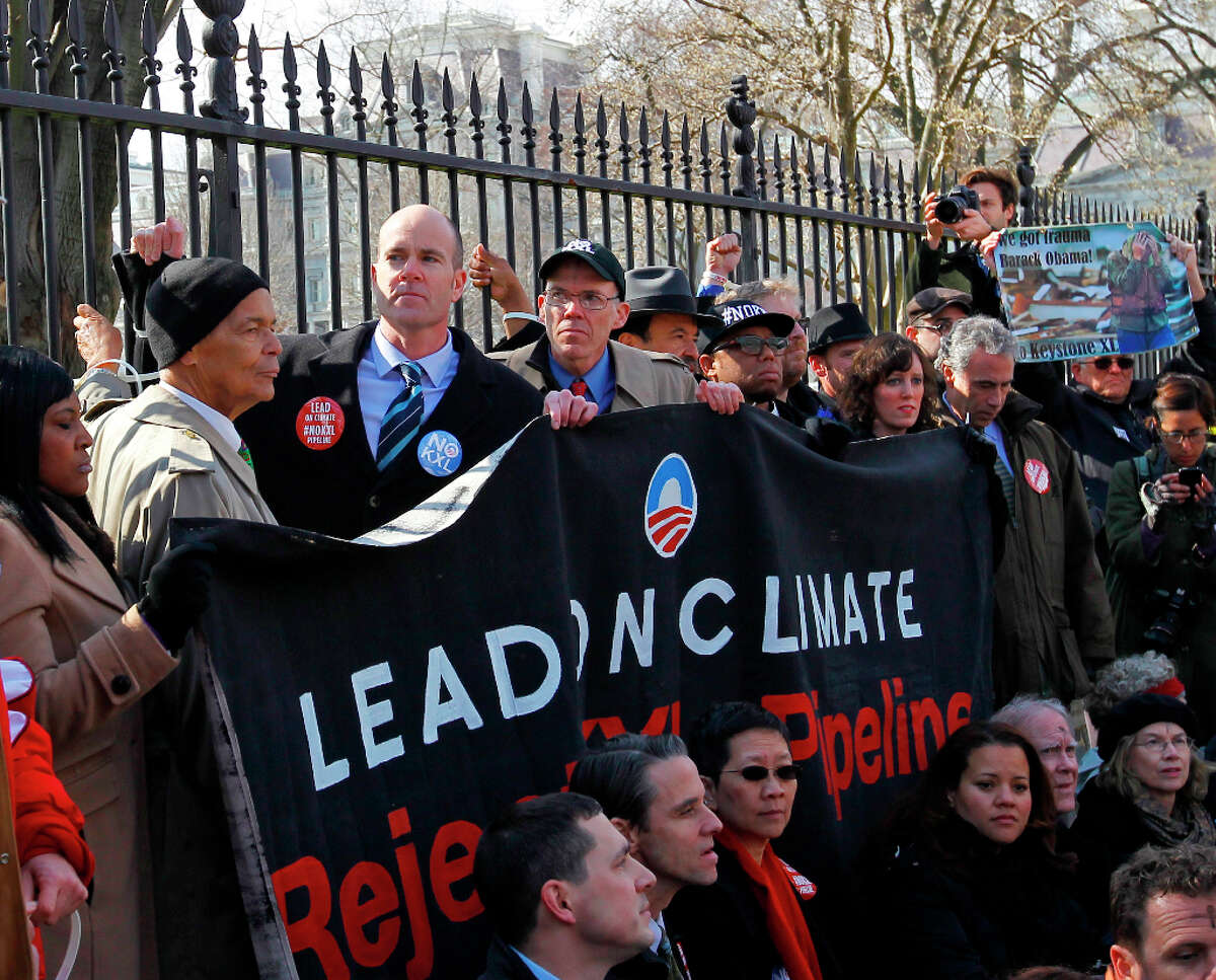Civil rights protester Julian Bond, left, and Sierra Club Executive Director Michael Brune, second from left, gather with activists in front of the White House in Washington, Wednesday, Feb. 13, 2013, as prominent environmental leaders tied themselves to the White House gate to protest the Keystone XL oil pipeline.