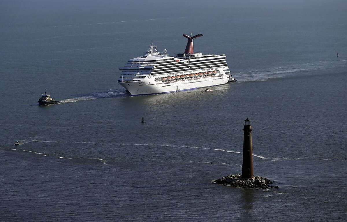 The disabled Carnival Lines cruise ship Triumph is towed to harbor off Mobile Bay, Ala., Thursday, Feb. 14, 2013. The ship with more than 4,200 passengers and crew members has been idled for nearly a week in the Gulf of Mexico following an engine room fire. (AP Photo/Gerald Herbert)