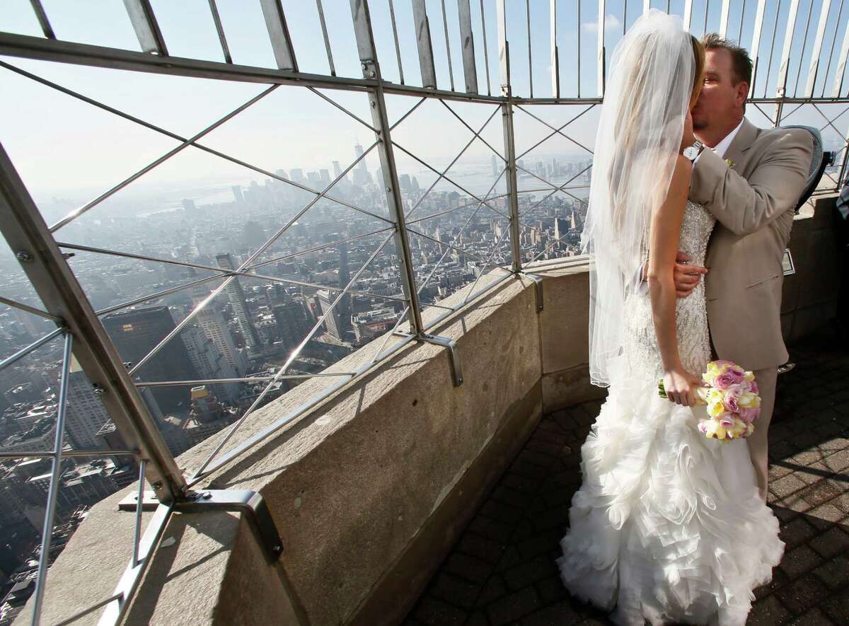 Newlyweds Danielle Brabham, 39, and Michael Lynch, 41, from Miami Shores, Fla., kiss while posing for pictures on the Empire State Building viewing platform after their Valentine's Day wedding on Thursday, Feb. 14, 2013 in New York. Brabham and Lynch were among three couples chosen for the 19th Annual Weddings Event, "Love is in the Air," designed by celebrity designer Preston Bailey, after submitting their personal love stories to the Empire State Building's Facebook page.