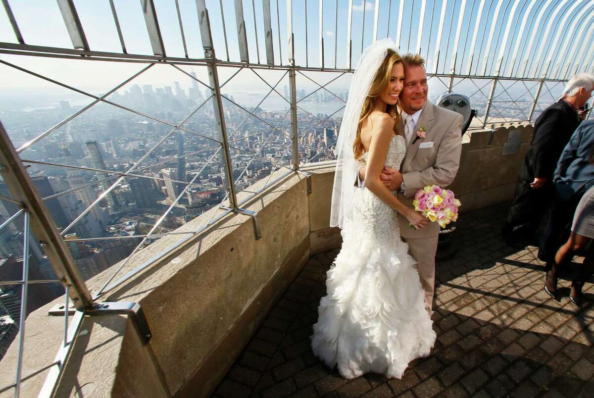 Newlyweds Danielle Brabham, 39, and Michael Lynch, 41, from Miami Shores, Fla., pose for pictures at the Empire State Building viewing platform after their Valentine's Day wedding on Thursday, Feb. 14, 2013 in New York. Brabham and Lynch were among three couples chosen for the 19th Annual Weddings Event, "Love is in the Air," designed by celebrity designer Preston Bailey, after submitting their personal love stories to the Empire State Building's Facebook page.