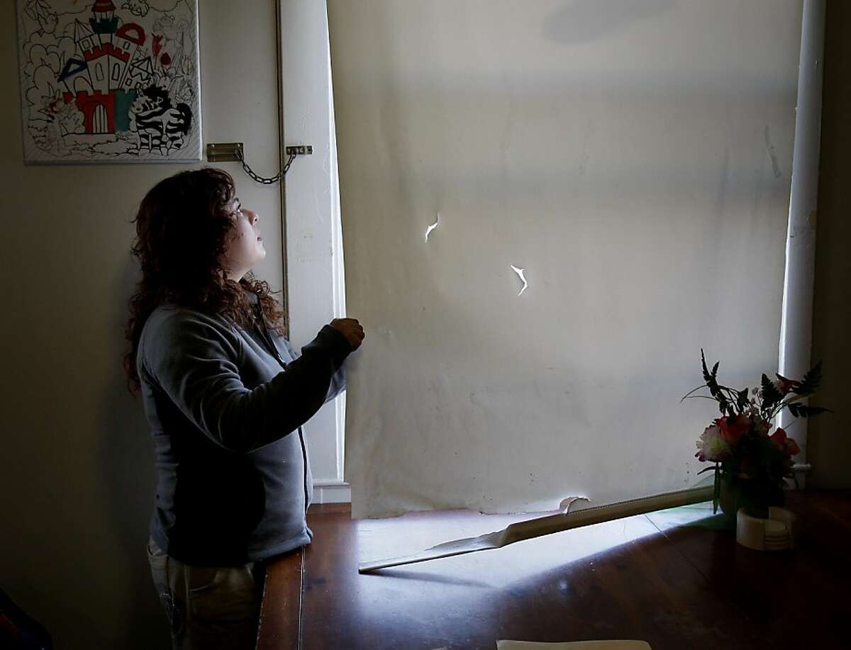 Rosalba Penaloza peers out the window of her apartment, she is often scared by other residents. Rosalba Penaloza and her two children live in Potrero Terrace, one of the most notorious public housing sites in San Francisco, Calif. She has been on an emergency transfer list for nine months but is still stuck. Her case provider, Karla Ramos, is trying to help her into a new home.