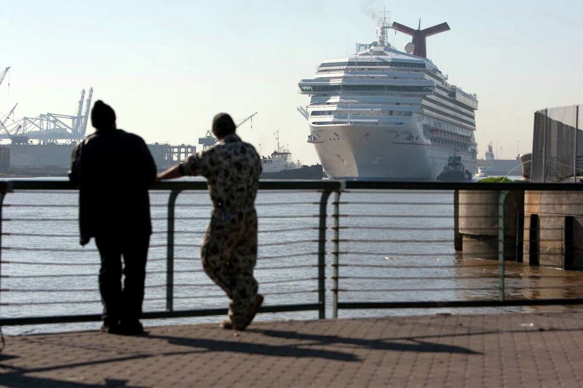 Richard Green, left, and Michael Cannon, of Mobile, looks on as the Carnival Triumph cruse ship is taken from the Alabama Cruise Terminal to be docked for repairs Friday, Feb. 15, 2013, in Mobile. The vessel became stranded after an engine fire leaving the 4,000 passengers floating at sea. The ship was towed to Mobile by a group of tugboats.