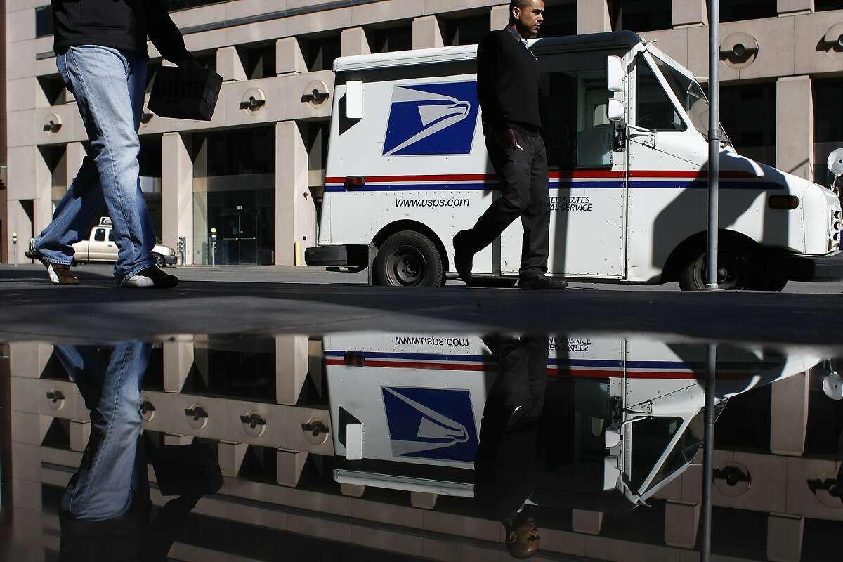 Passersby walk past a mail truck in front of the Rincon Center postal office on Friday, Feb. 13. The Postal Service is planning to cut Saturday services completely.