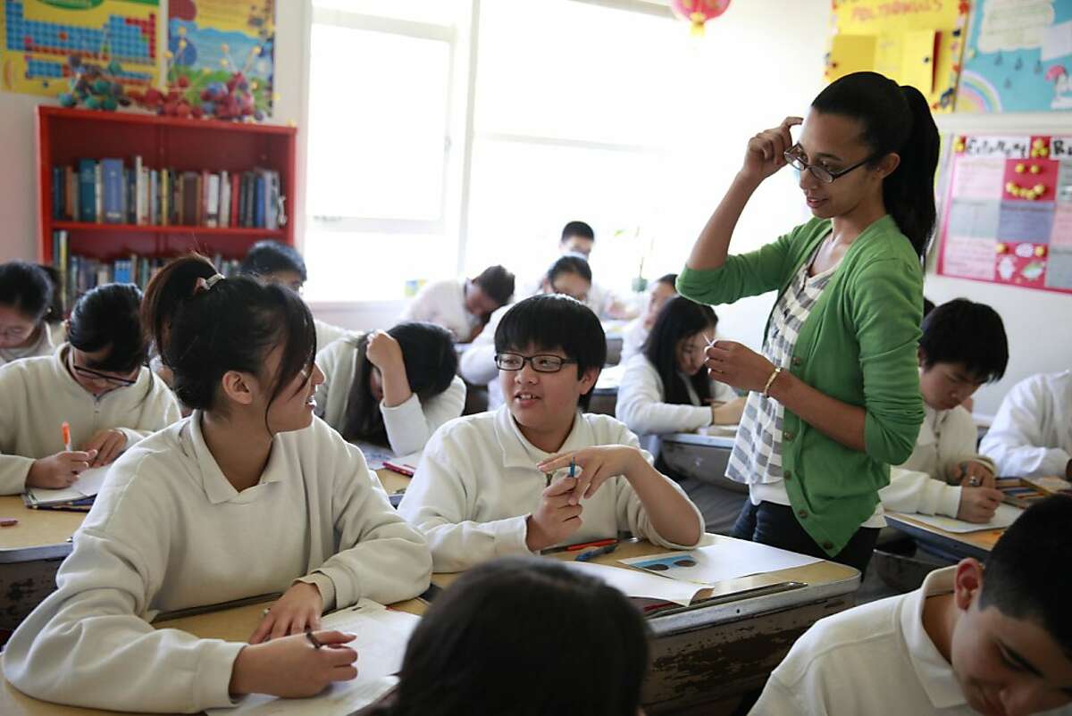 Eighth grade teacher Stacey Adams (right) talks with eighth grader Angie Zhu (left), 15, and Vincent Nguyen (center), 13, as they work on an assignment during Language Arts at the American Indian Public Charter School on Wednesday, February 13, 2013 in Oakland, Calif.
