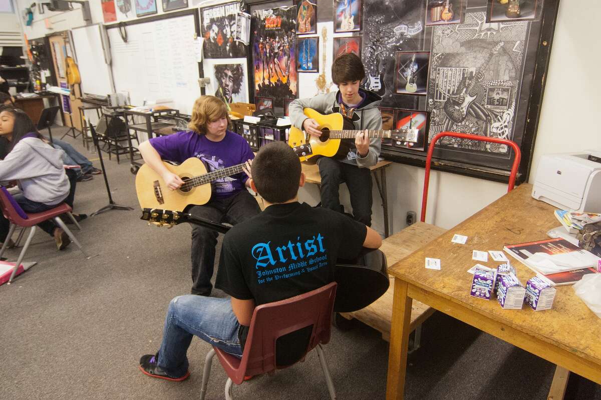 Johnston eighth-graders Sonny Lund, 14, Matthew McCleskey, 14, and Cameron Wieman, 14, practice guitar during class at Johnston Middle School.