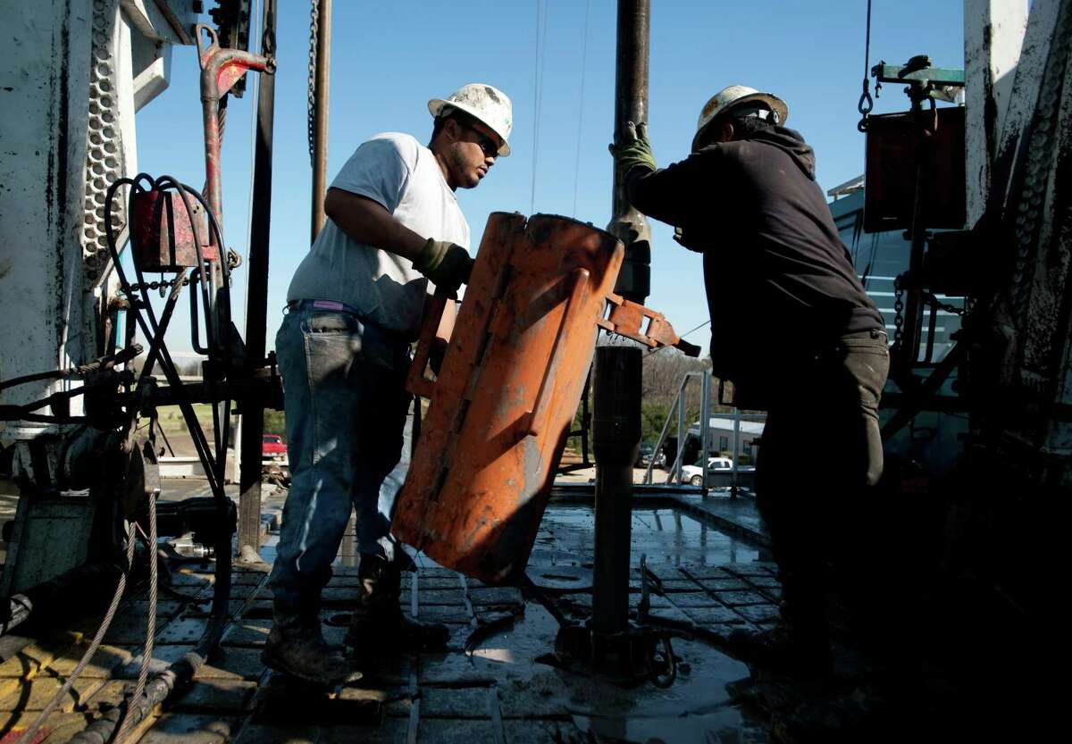 Trinidad Drilling floorhands Julio Serrato, left, and Jaime Gonzalez work on the drilling of a Chesapeake Energy Corp. natural gas site in the Fort Worth area.﻿