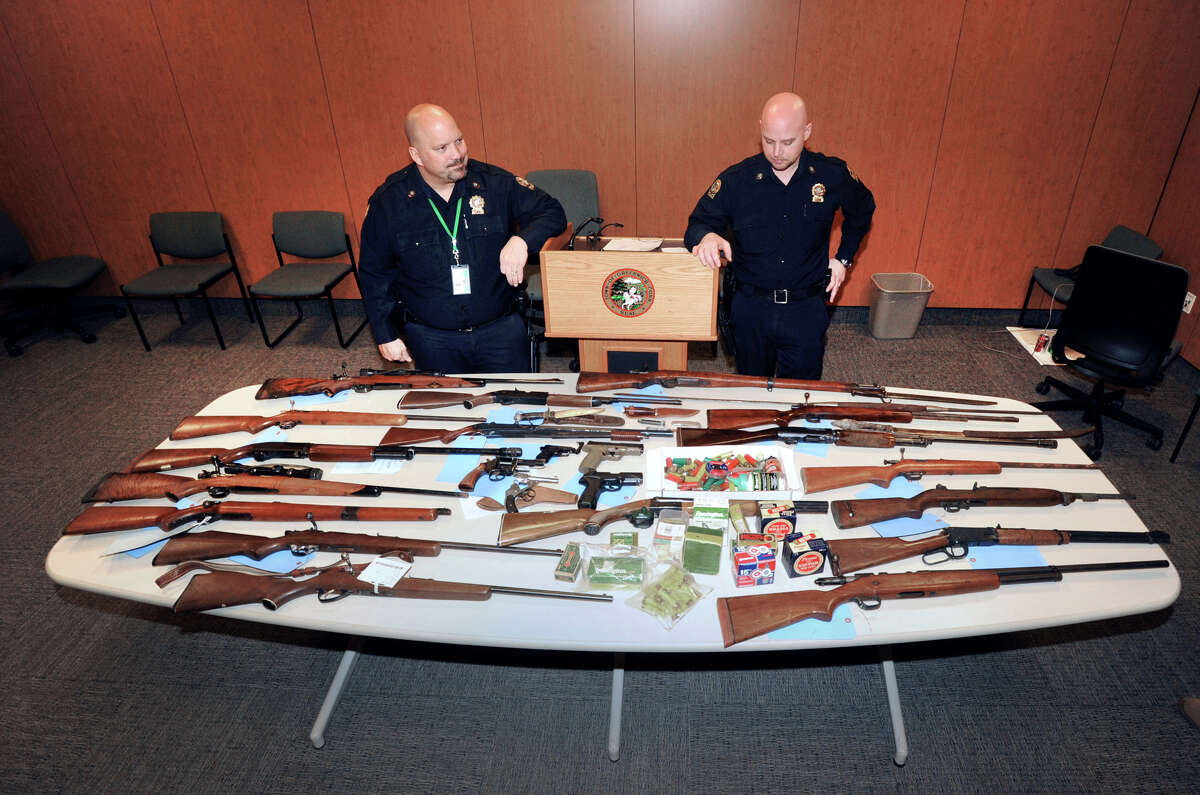 Greenwich Police Detective, Anthony Fiscella, left, and Greenwich Police Officer, Keith Hirsch, display weapons turned in to the police during the Weapons Turn In program held at Greenwich Police Headquarters, Saturday, Feb. 23, 2013. The weapons included 14 long guns, 3 pistols, 3 BB pistols, 3 BB rifles, 2 BB pistols, 5 knives, 1 sword and 1 spear.