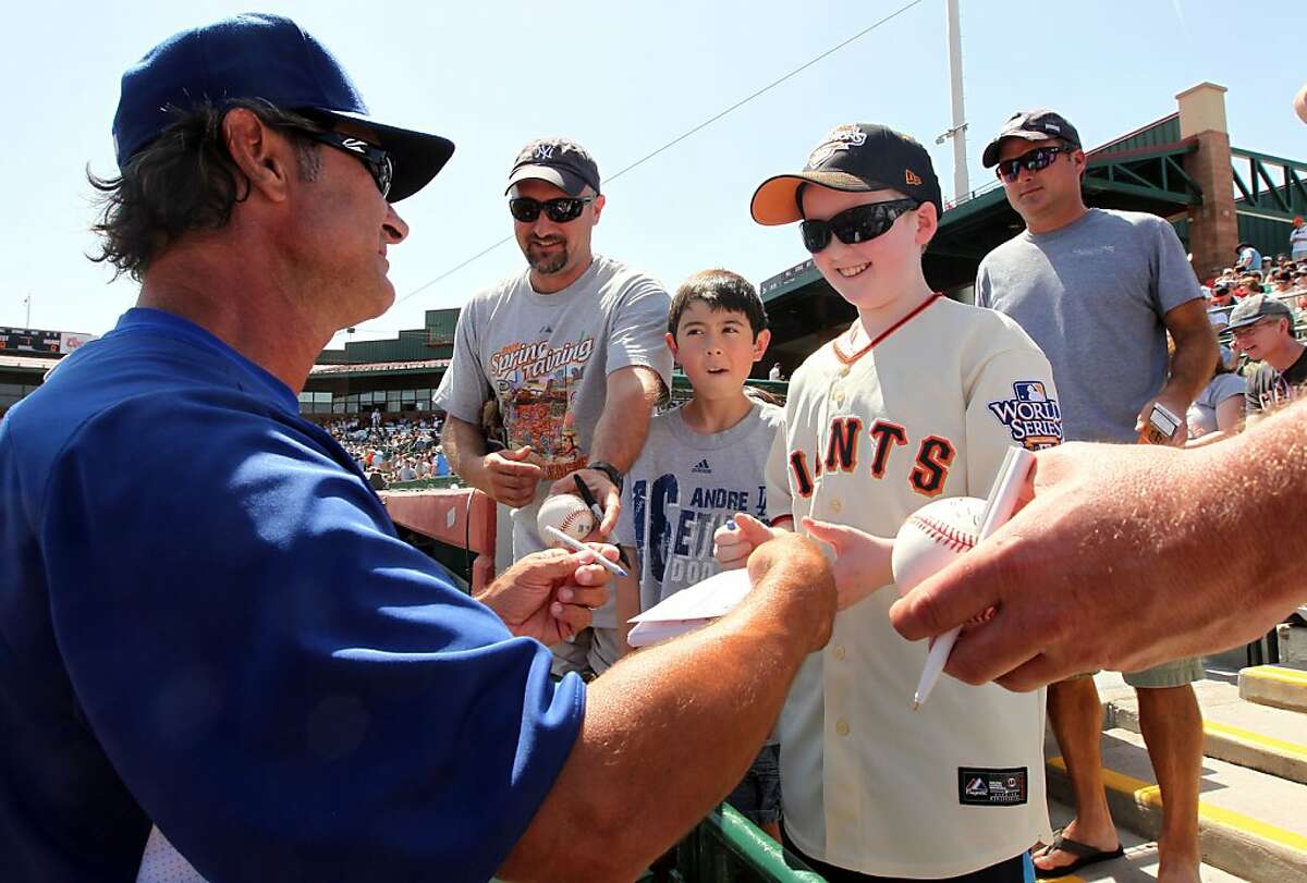 Los Angeles Dodgers manager Don Mattingly signs an autograph for San Francisco Giants fan Kenny Meyer 12, from Oregon, before a spring training baseball game against the Giants, Wednesday, March 28, 2012, in Scottsdale, Ariz.