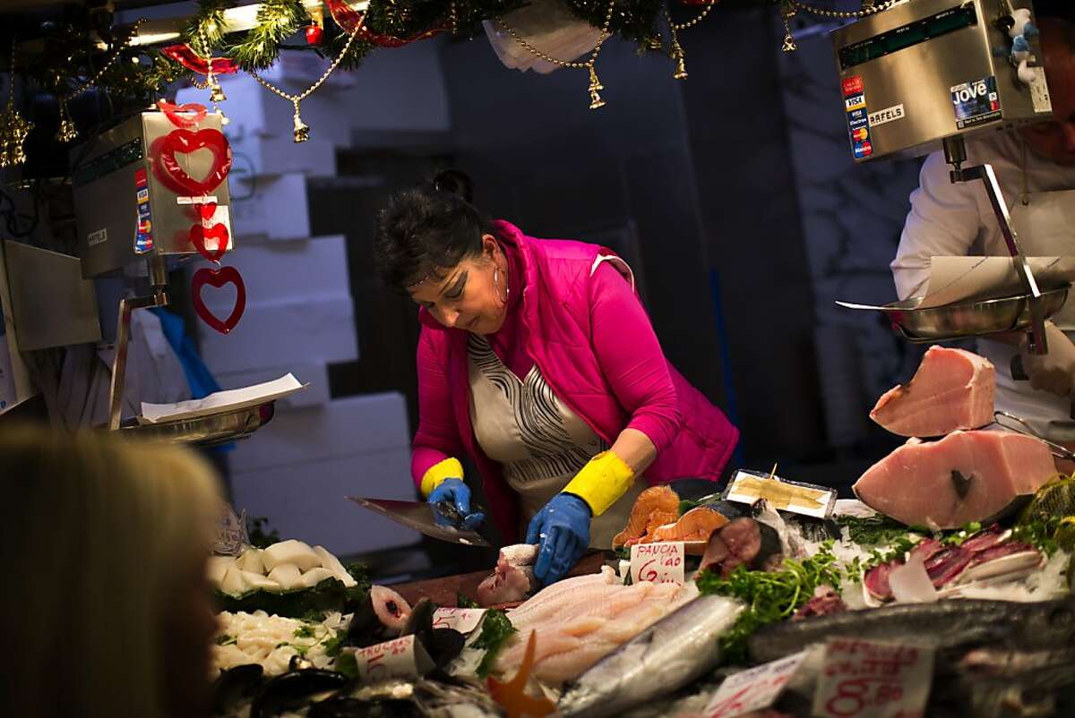 FILE - In this Thursday Jan. 17, 2013 file photo, a fishmonger prepares fish for a client in a market in Barcelona, Spain. Mediterranean diets have long been touted as heart-healthy, but that's based on observational studies. Now, one of the longest and most scientific tests suggests this style of eating can cut the chance of suffering heart-related problems, especially strokes, in older people at high risk of them. Results were published online Monday, Feb. 25, 2013 by the New England Journal of Medicine. (AP Photo/Emilio Morenatti)