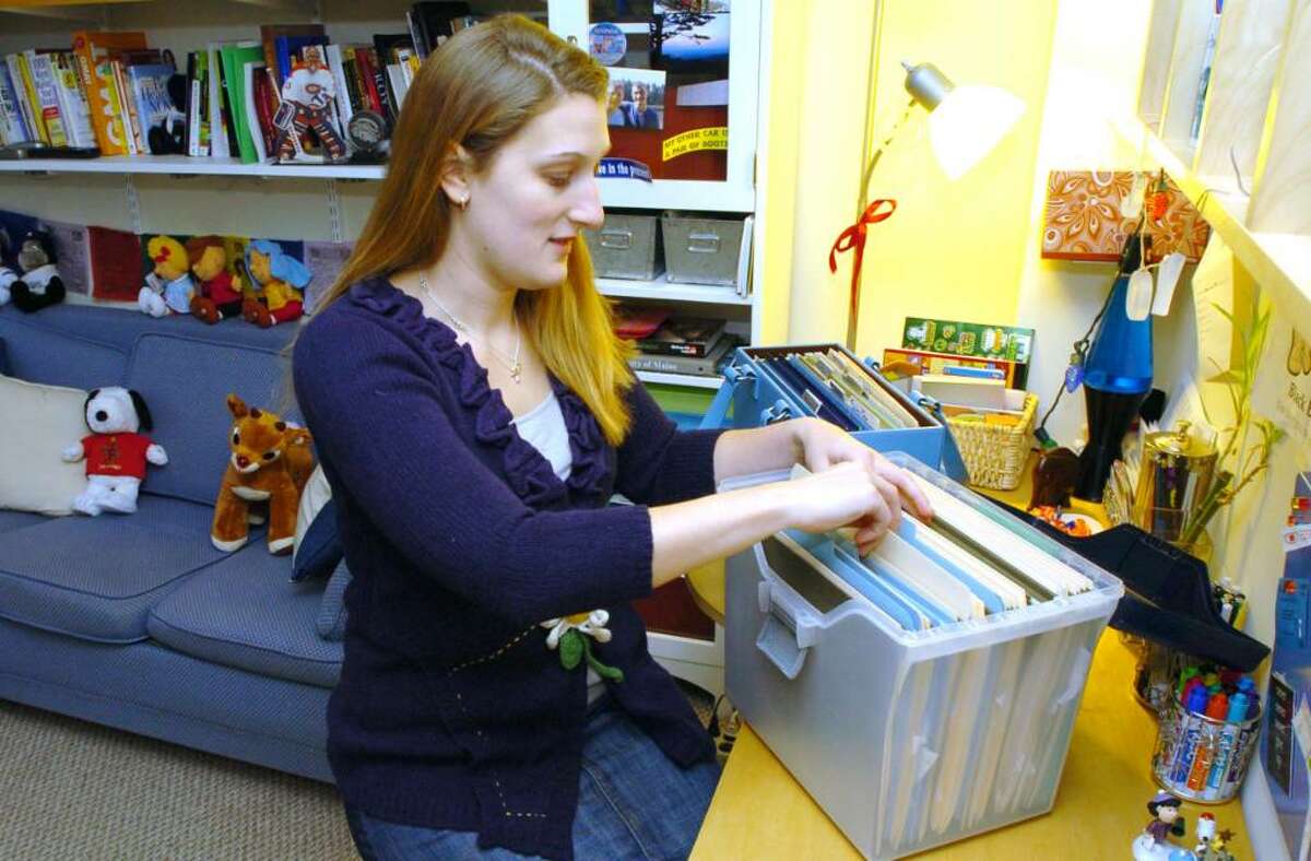Bonnie Dewkett, of Danbury, looks over clients files at her home Monday, Dec. 28, 2009.