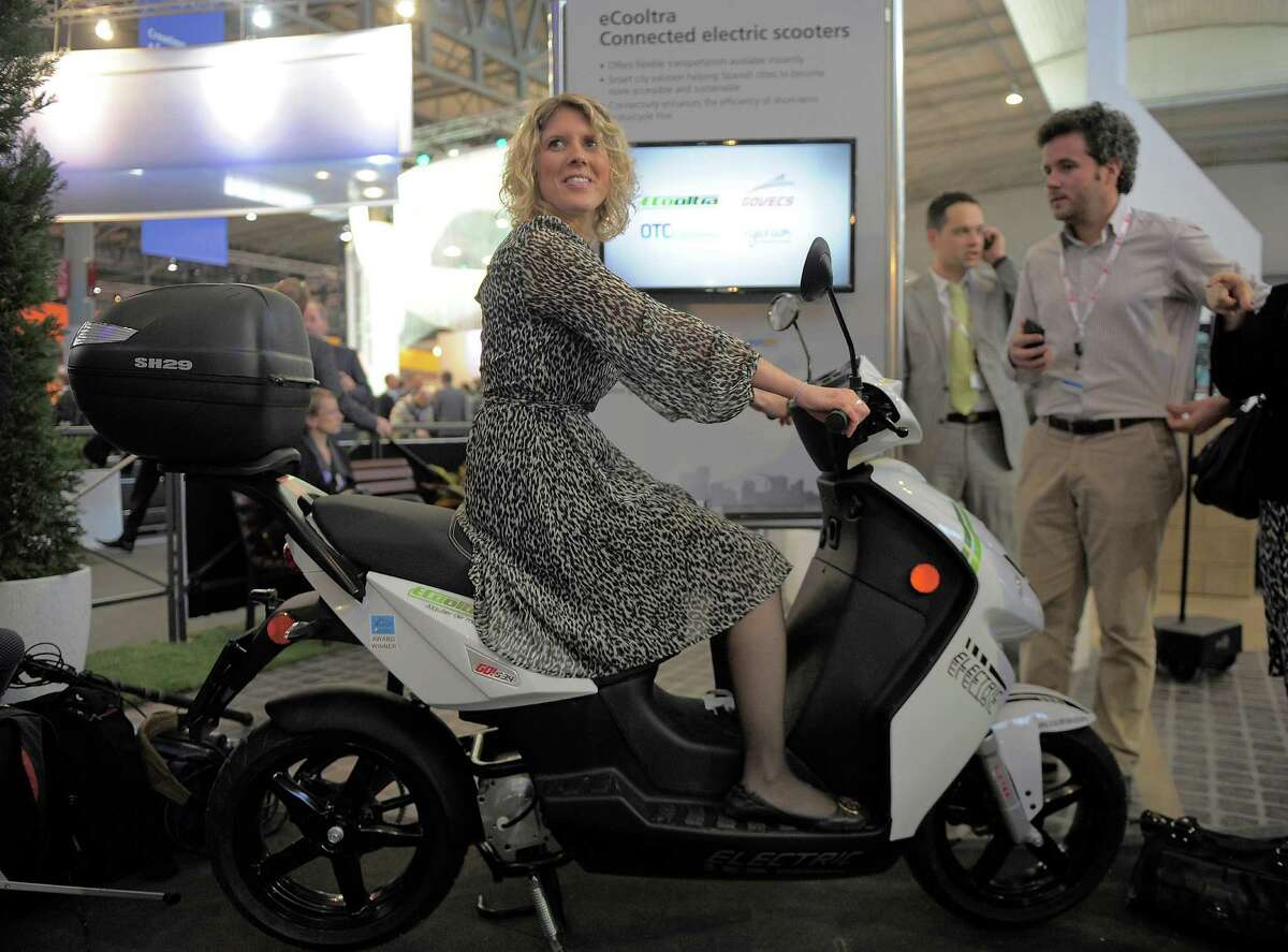 In this Tuesday, Feb. 26, 2013, photo, a woman sits on an eCooltra Connected electric scooters at the Mobile World Congress, the world's largest mobile phone trade show, in Barcelona, Spain. The first wave of the wireless revolution was getting people to talk to each other through cellphones. The second, it seems, will be getting things to talk to each other, with no human intervention: cars that talk to your insurance company?’s computers, bathroom scales that talk to your phone, and electric meters that talk to your air conditioners. So-called machine-to-machine technology all the buzz at this year?’s largest wireless trade show, and some analysts believe these types of connection will outgrow the traditional phone business in less than a decade. (AP Photo/Manu Fernandez)