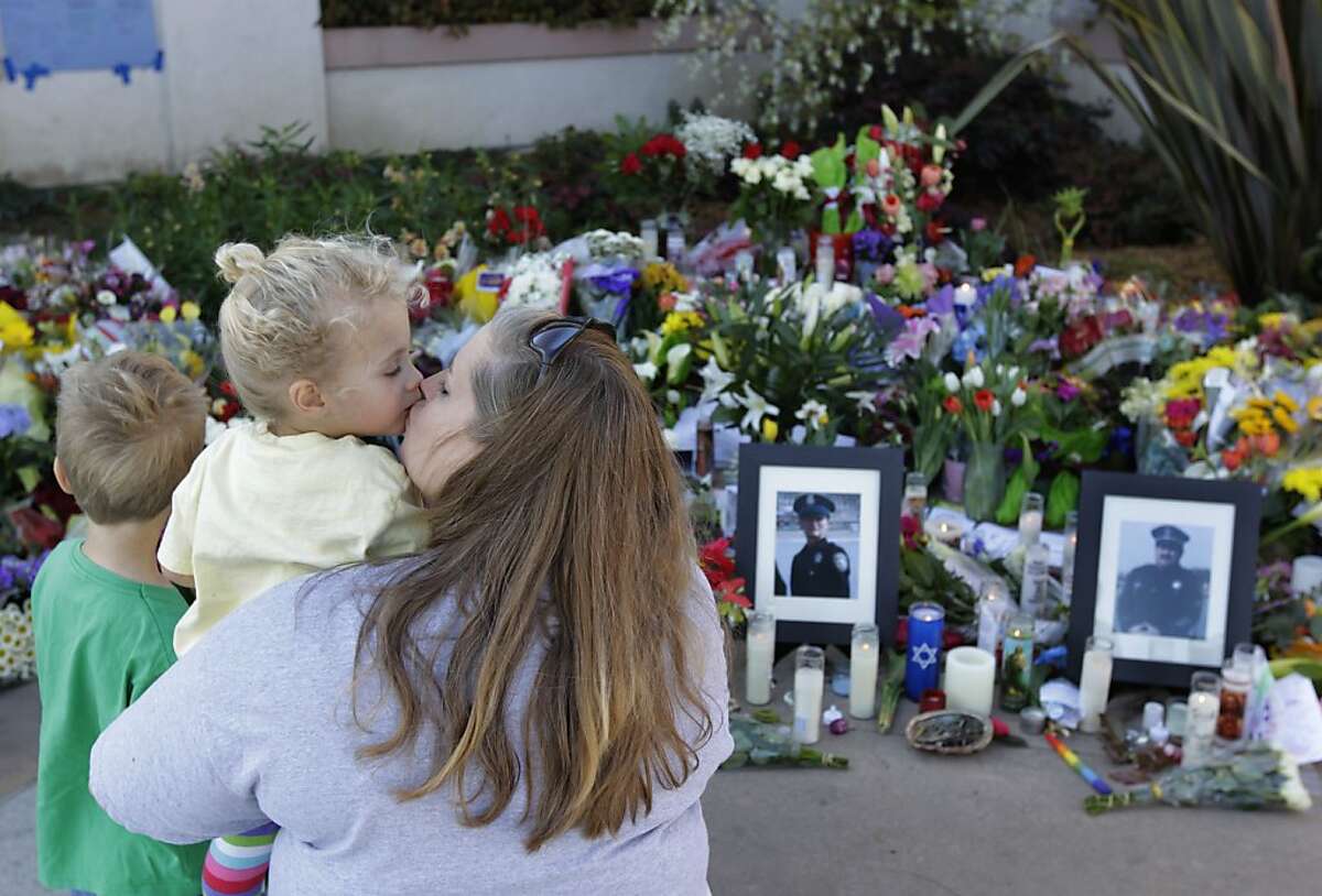 Chris Breeden visits the memorial in front of police headquarters with her children James, 5, and Hollie, 3, in Santa Cruz, Calif. on Thursday, Feb. 28, 2013. Tuesday's gun battle resulting in the deaths of two Santa Cruz detectives and the suspect they were interrogating caps several weeks of unusually violent crimes that are rare for this beachfront town.