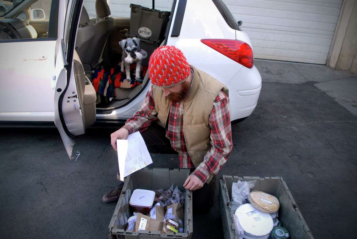 Justin Bassett and his dog "Hobo" drive down to Connecticut once a week from Vermont making deliveries for Graze, a artisanal food company. He loads a rental car in Stamford, Conn. on Monday March 4, 2013 after his truck broke down.