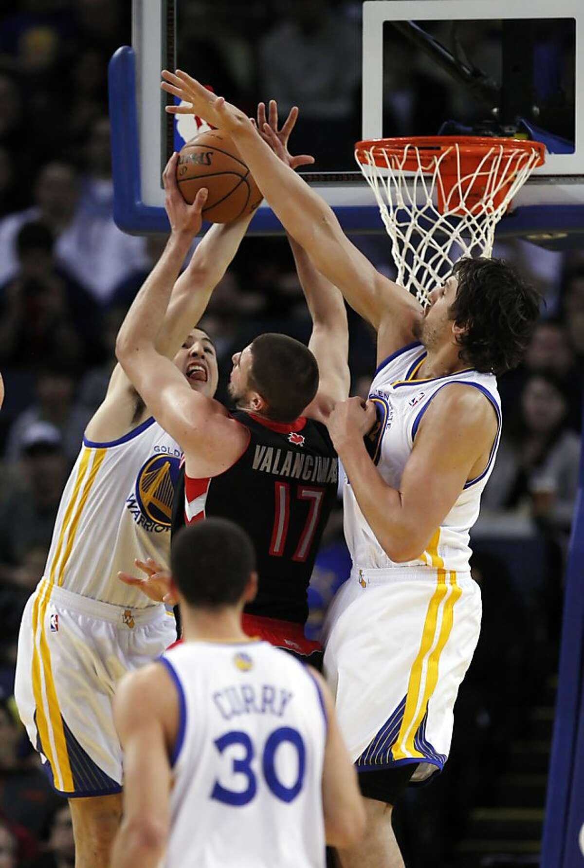 Klay Thompson, left, and Andrew Bogut, right, guard against Toronto's Jonas Valanciunas in the first half. The Golden State Warriors played the Toronto Raptors at Oracle Arena in Oakland, Calif., on Monday, March 4, 2013.