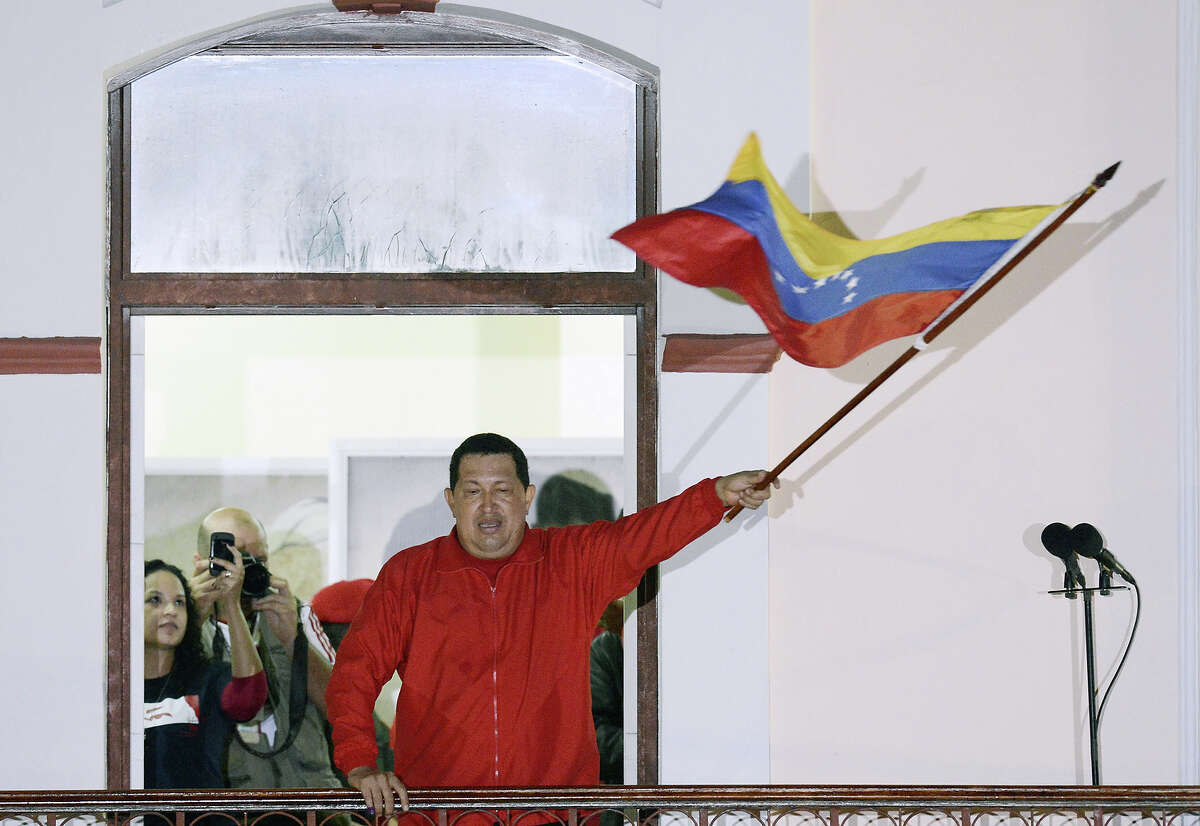 Venezuelan President Hugo Chavez waves a Venezuelan flag while speaking to supporters after receiving news of his reelection in Caracas on October 7, 2012. According to the National Electoral Council, Chavez was reelected with 54.42% of the votes, beating opposition candidate Henrique Capriles, who obtained 44.97%. AFP PHOTO/JUAN BARRETO (Photo credit should read JUAN BARRETO/AFP/GettyImages)