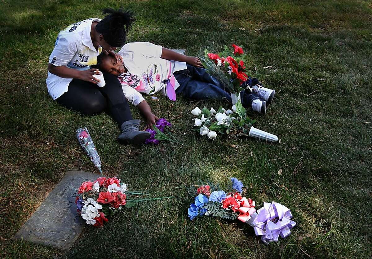 Andrea James comforts her son Andre Landoer, 8, as they sit by the grave of her older son Lamont Price, 17, Saturday, February 16, 2013, at Rolling Hills Memorial Park in Richmond on the one-year anniversary of his murder.