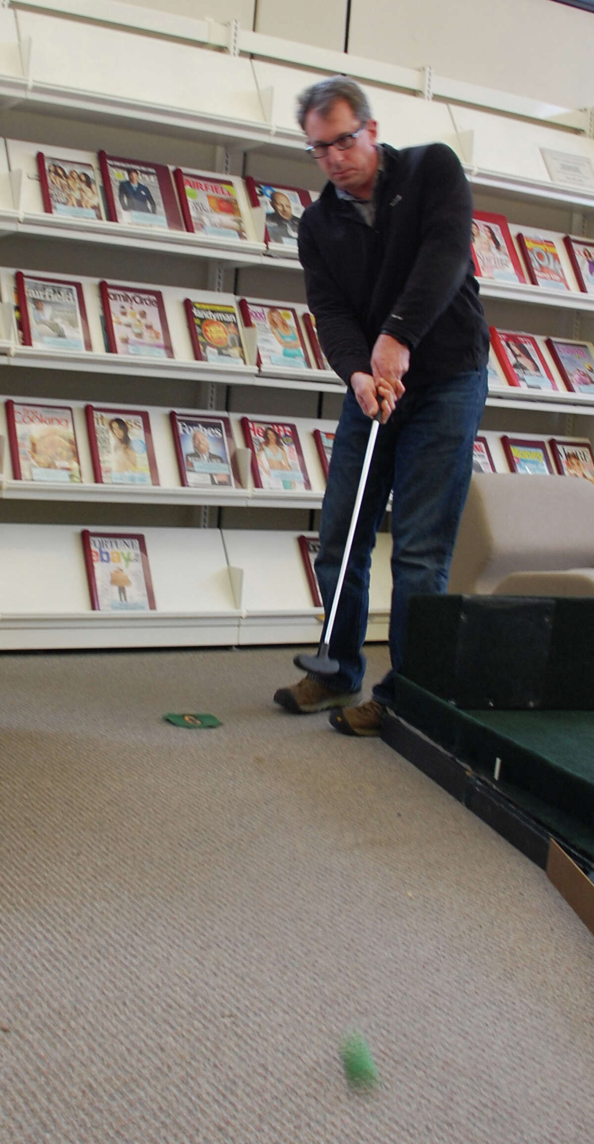 Neal Fink of Fairfield unleashes a putt on a "green" set up Sunday for a mini golf fundraiser at Fairfield Woods Branch Libray. FAIRFIELD CITIZEN, CT 3/3/13