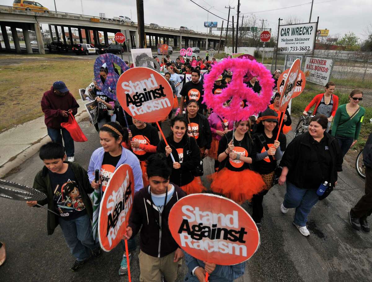 People carry signs during the 23rd annual International Women's Day March & Rally in San Antonio Saturday, March 9, 2013. The purpose of the march is to raise awareness about domestic violence, pay-equity, and the struggles of low-income workers and families.