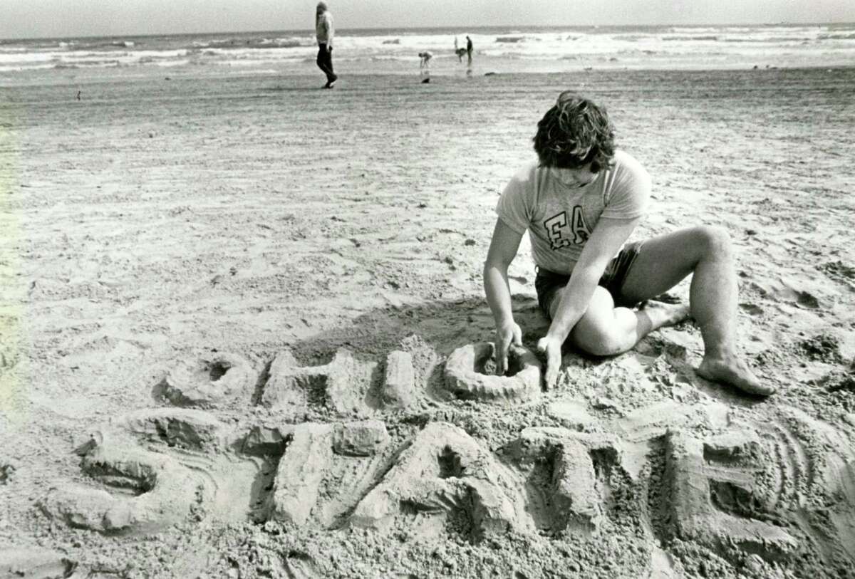 March 18, 1984: Terry Chapman, 22, has his way on Stewart Beach in Galveston as he builds a sand memorial to his alma mater, Ohio State. Chapman is an avionics engineering student down here on spring break.
