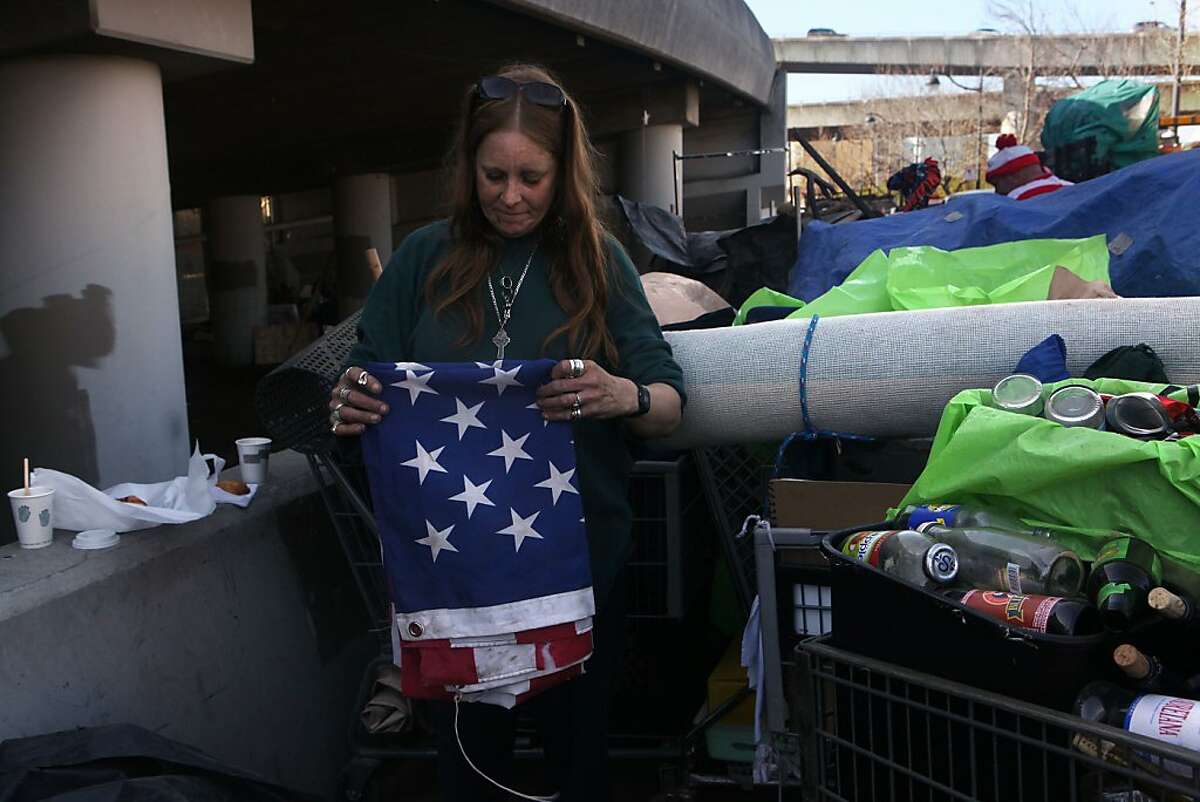 Lisa Ross folds a flag given to her and her boyfriend beneath the Interstate 280 on-ramp in San Francisco, Calif., as she packs belongings on Monday, March 11, 2013.