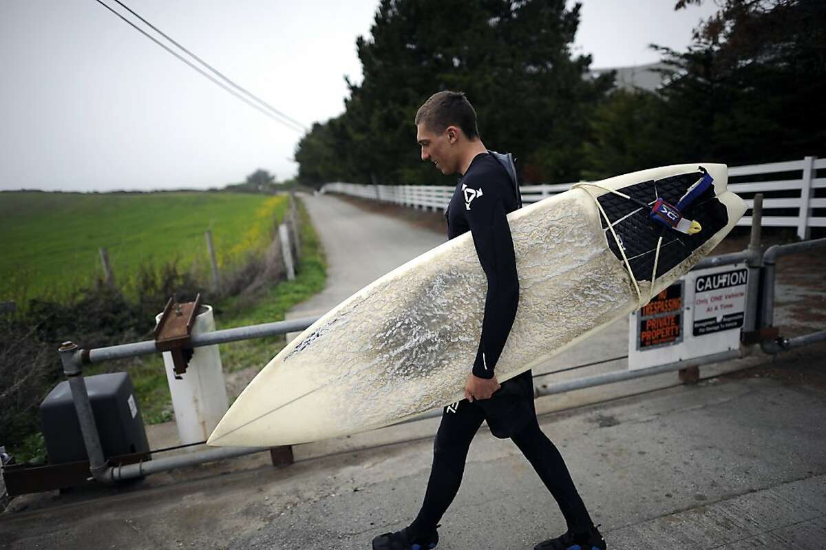 Surfer Konrad Wallace of El Granada walks past the gate on the now private road on his way to Martin's Beach in Half Moon Bay Tuesday March 12th, 2013.