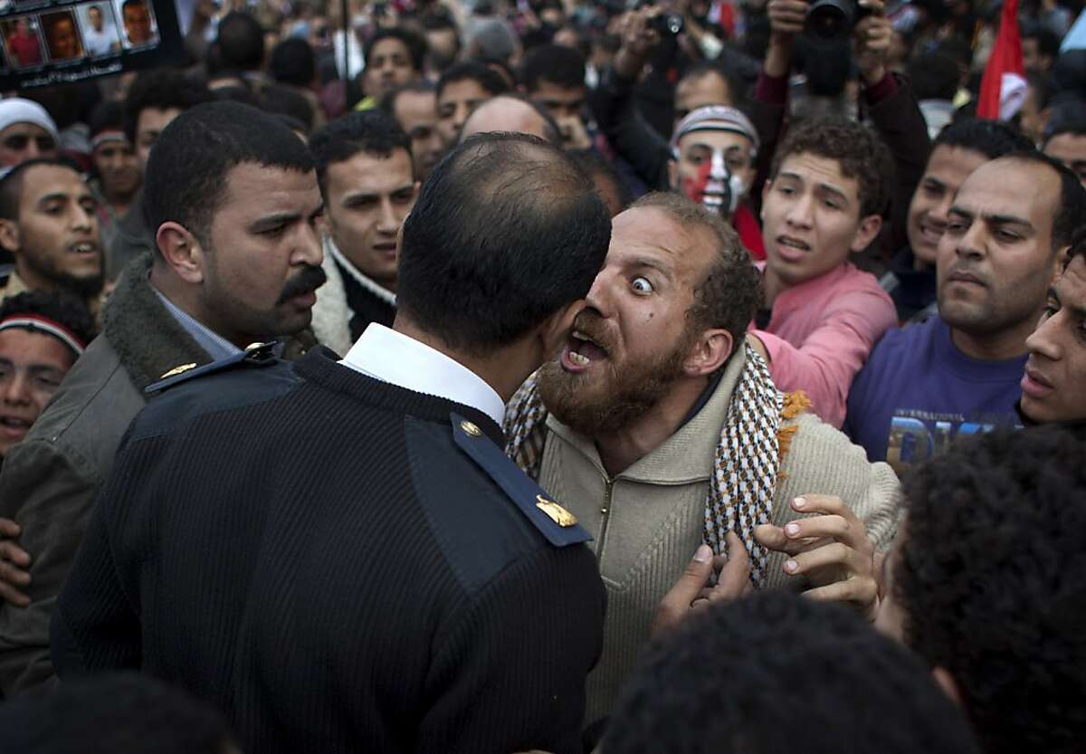FILE - In this Sunday, Feb. 13, 2011 file photo, an Egyptian protester, center right, argues with a police officer in Tahrir Square in downtown Cairo, Egypt. A government inquiry into the deaths of nearly 900 protesters during Egypt's uprising has concluded police were behind nearly all the killings and used snipers on rooftops overlooking Tahrir Square to shoot into the huge crowds. The report, parts of which were obtained by The Associated Press, is the most authoritative account of the killings and determines the deadly force used could only have been authorized by ousted President Hosni Mubarak's security chief, with the president's full knowledge. (AP Photo/Emilio Morenatti, File)