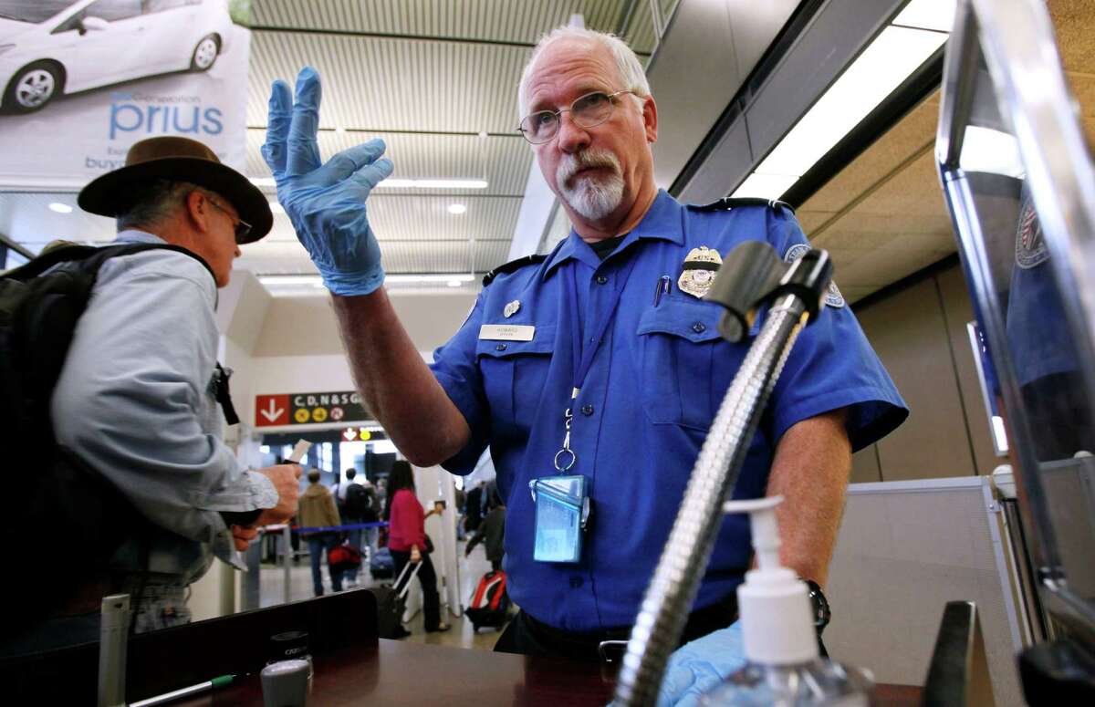 FILE - In this Jan. 4, 2010 file photo, TSA officer Robert Howard signals an airline passenger forward at a security check-point at Seattle-Tacoma International Airport in SeaTac, Wash. Flight attendants, pilots, federal air marshals and even insurance companies are part of a growing backlash to the Transportation Security Administration?’s new policy allowing passengers to carry small knives and sports equipment like souvenir baseball bats and golf clubs onto planes. (AP Photo/Elaine Thompson, File)