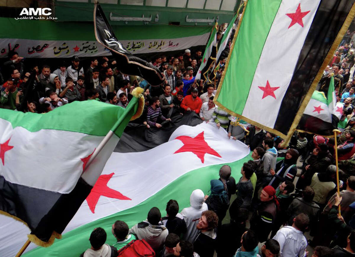 In this citizen journalism image provided by Aleppo Media Center AMC which has been authenticated based on its contents and other AP reporting, anti-Syrian regime protesters, wave the Syrian revolutionary flags during a protest to mark the second anniversary of the their uprising, in Aleppo, Syria, Friday March 15, 2013. The chief of Syria's main, western-backed rebel group marked the second anniversary of the start of the uprising against President Bashar Assad on Friday by pledging to fight until the "criminal" regime is gone. (AP Photo/Aleppo Media Center, AMC)