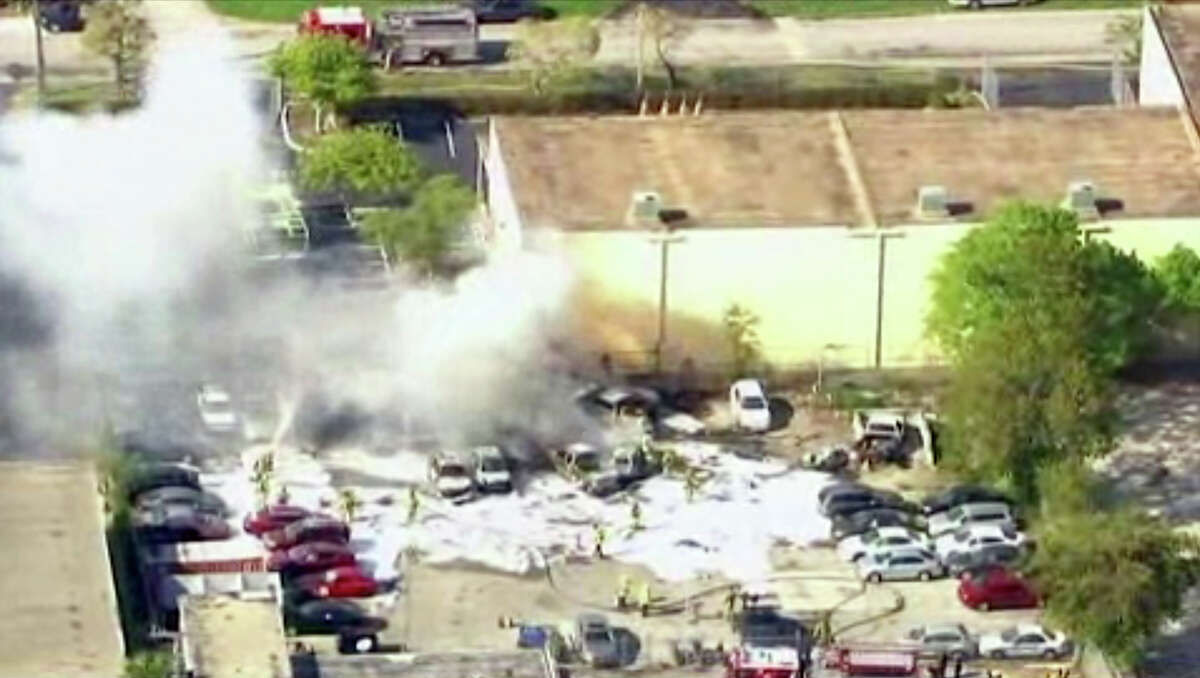 In this image taken from video, first responders work to extinguish burning vehicles after a small plane crashed into a parking lot near Fort Lauderdale Executive Airport in Fort Lauderdale, Fla. Friday afternoon, March 15, 2013, killing all three people onboard and burning about a dozen cars. No one on the ground was hurt. (AP Photo/APTN)