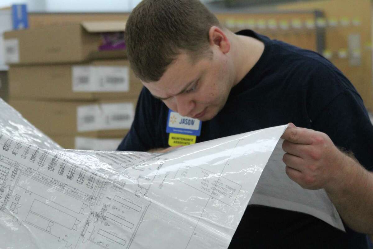 Jason Parsons, 27, maintainance associate, pores over a Walmart store map as he helps prepare the Helotes site for its April 10 opening. It's his first job, he says, and, as a college student, he says, the company does "really well working with a college schedule."